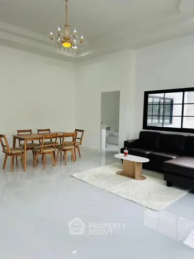 Spacious living room with modern chandelier and elegant dining area.
