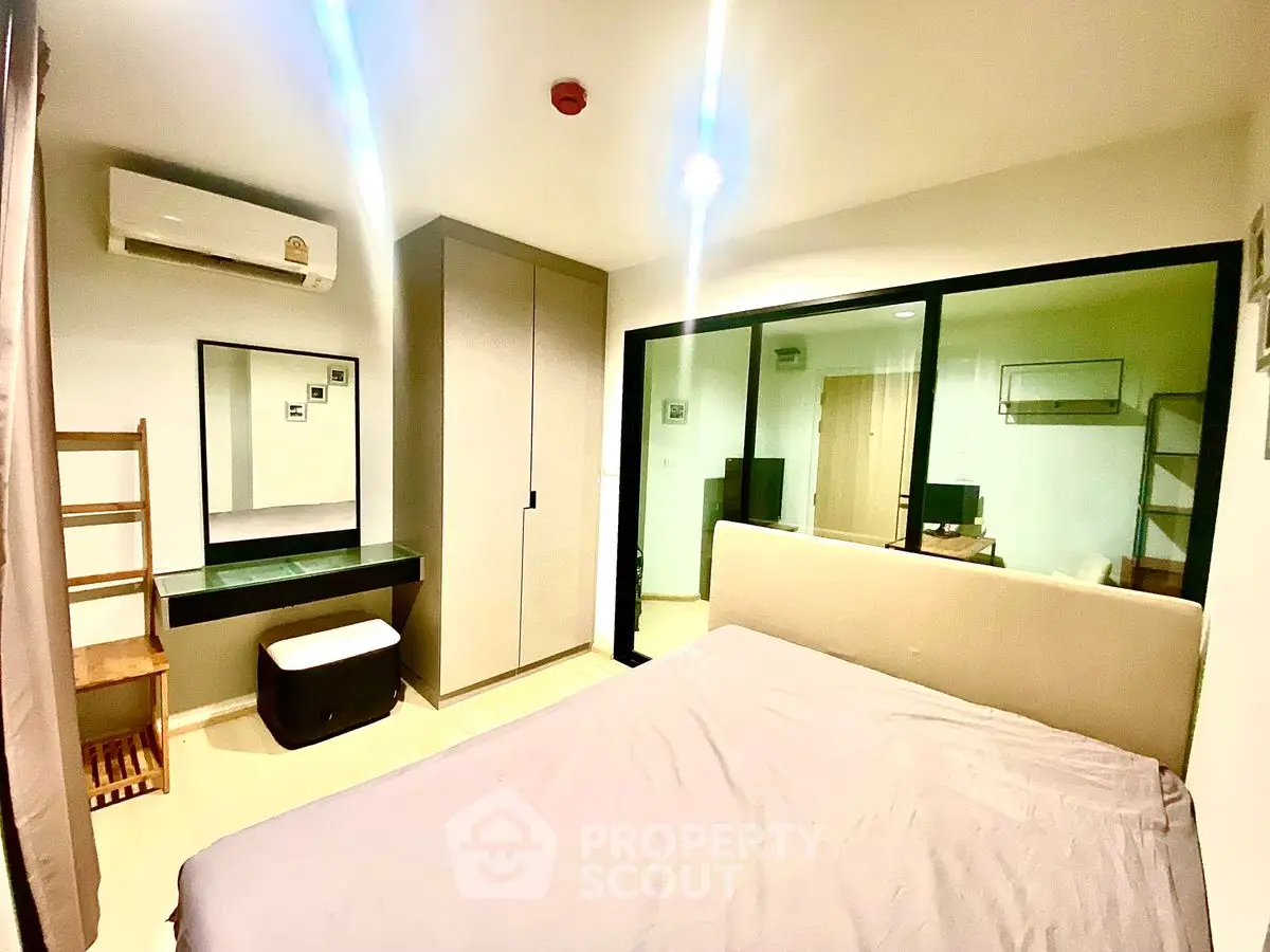 Modern bedroom with large window and sleek furnishings in a stylish apartment.