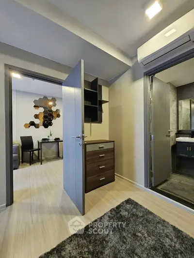 Modern apartment interior with open door to study and bathroom, featuring sleek design and air conditioning.