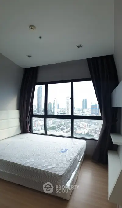 Modern bedroom with large window offering stunning city view in high-rise apartment.