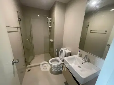 Modern bathroom with glass shower and sleek fixtures in a contemporary apartment.