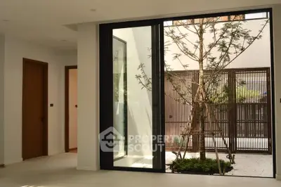 Modern interior with large glass doors opening to a small garden courtyard, featuring sleek design and natural light.