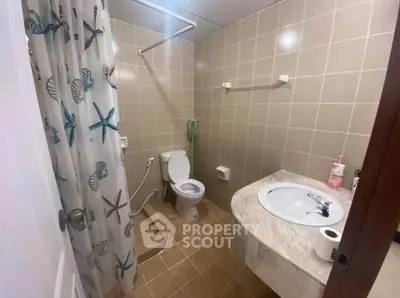 Cozy bathroom with tiled walls, shower curtain, and marble sink countertop.