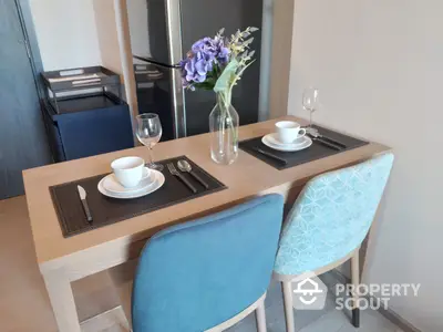 Cozy dining space with modern wooden table set for two, elegant blue chairs, and a bouquet adding a touch of sophistication.