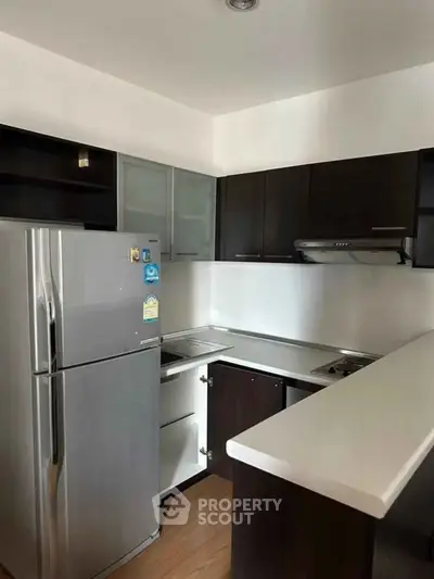 Modern kitchen with sleek cabinets and stainless steel fridge in a stylish apartment.