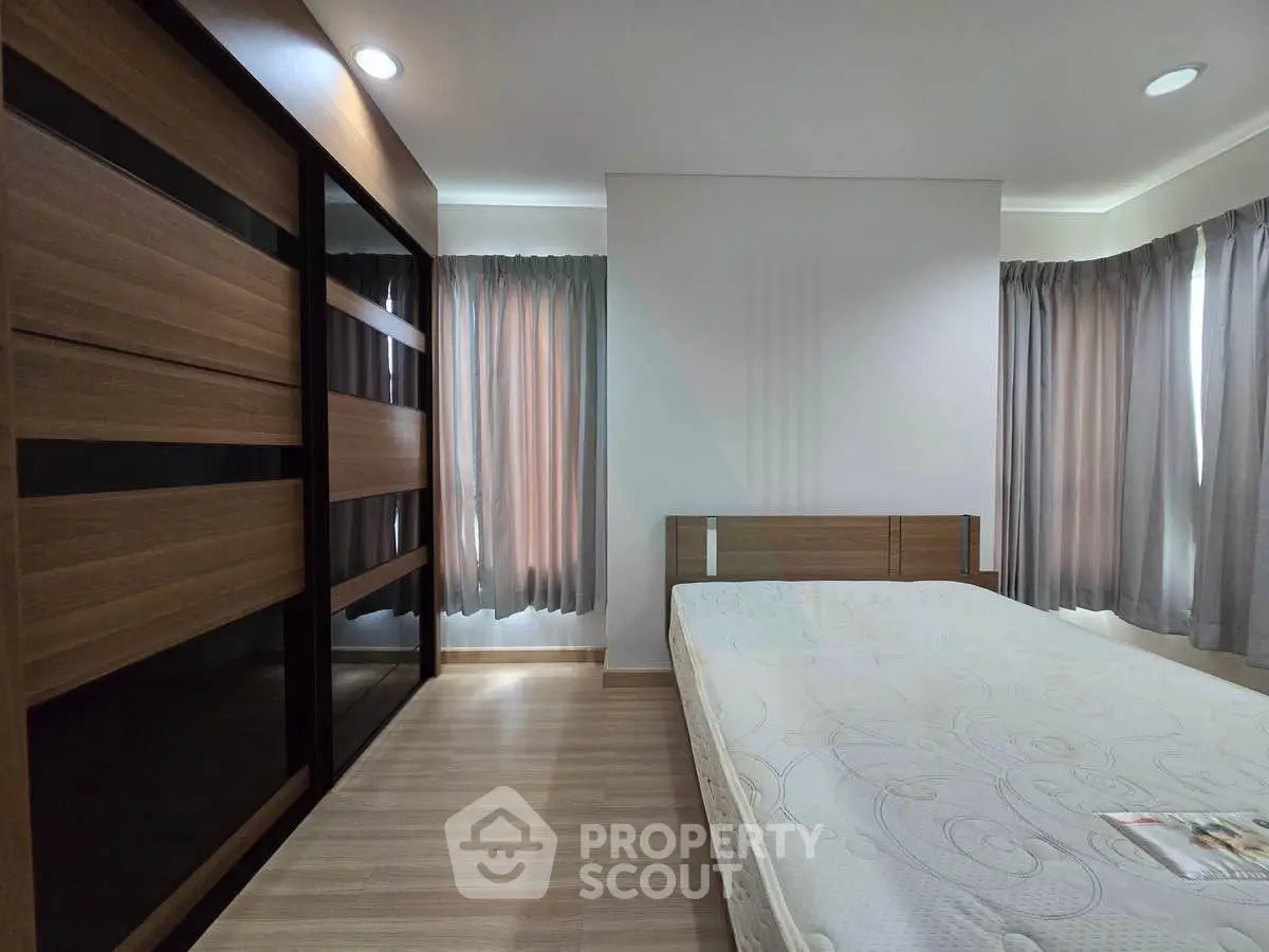 Spacious bedroom with modern wooden wardrobe and large windows for natural light.