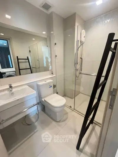Modern bathroom with glass shower enclosure and sleek fixtures in a contemporary apartment.
