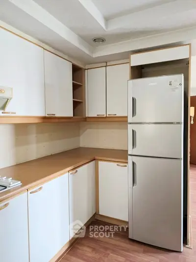 Modern kitchen with sleek cabinets and stainless steel fridge in a cozy apartment.