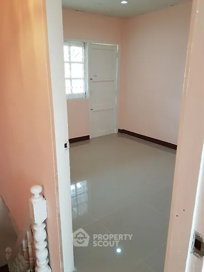 Cozy small room with glossy tiled floor and soft pink walls, perfect for a study or storage space.