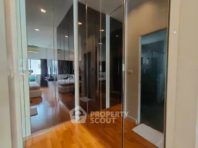 Spacious modern bedroom with mirrored closet doors and wooden flooring