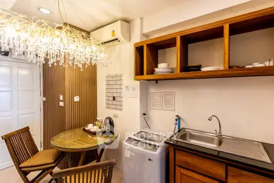 Charming kitchen with wooden cabinets, washing machine, and elegant chandelier lighting.