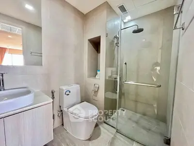 Modern bathroom with glass shower and sleek fixtures in contemporary apartment.