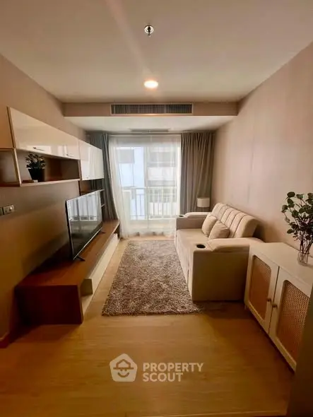 Modern living room with cozy sofa, stylish TV unit, and natural light from balcony.