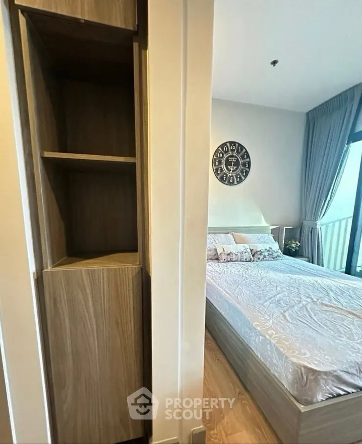 Modern bedroom with stylish decor and balcony view, featuring a cozy bed and elegant wooden shelving.