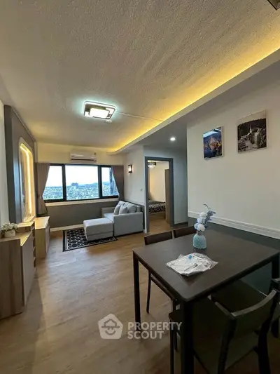 Spacious living room with modern decor and city view, featuring a cozy sofa and dining area.