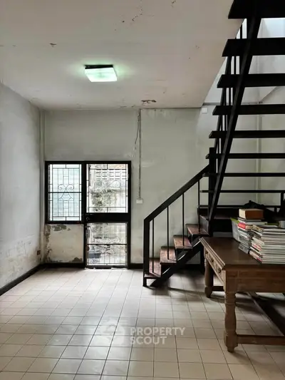 Spacious interior with modern staircase and natural light, ideal for creative living or office space.