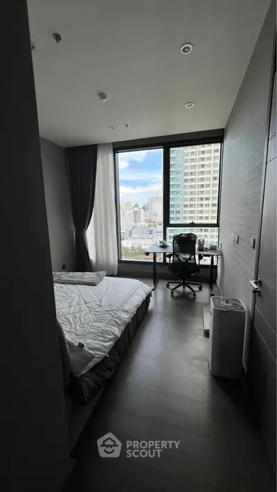 Modern bedroom with city view and workspace, featuring large windows and sleek design.