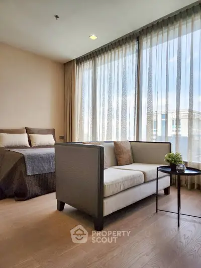 Modern bedroom with cozy sofa and large windows offering natural light