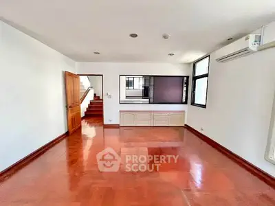 Spacious living room with wooden flooring and large windows for natural light.
