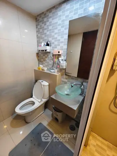 Modern bathroom with glass sink and tiled walls in cozy apartment.