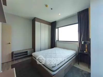 Modern bedroom with large window and stylish furnishings in a contemporary apartment.