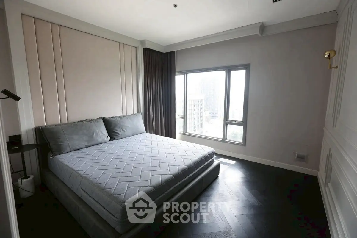 Modern bedroom with large window and stylish decor in urban apartment.