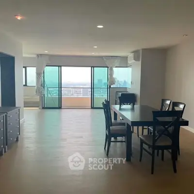 Spacious living room with dining area and city view balcony in modern apartment.