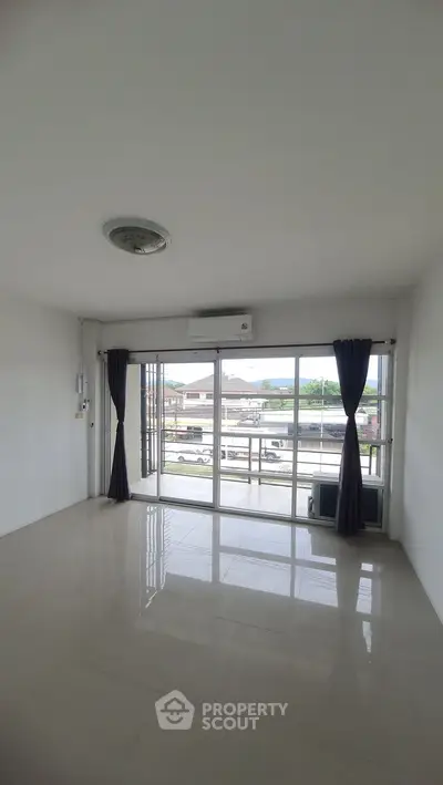 Spacious living room with large windows and balcony access, offering ample natural light and modern design.