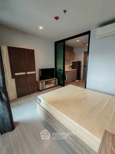 Modern studio apartment with open layout, featuring a cozy bedroom and compact kitchen area.