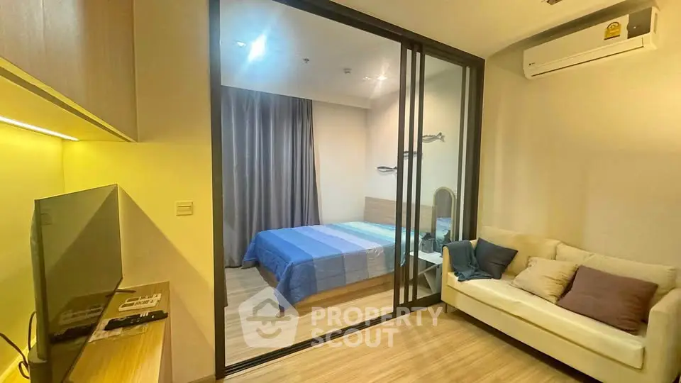 Modern apartment with cozy living room and bedroom separated by glass partition, featuring stylish decor.