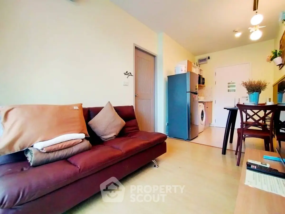 Cozy living room with modern kitchen and dining area, featuring a comfortable sofa and stylish decor.