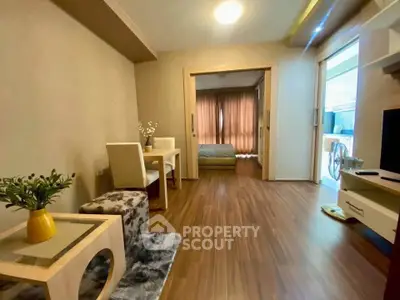 Modern open-plan living room with cozy dining area and view into bedroom, featuring stylish decor and wooden flooring.