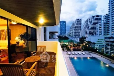 Luxurious balcony view overlooking a stunning pool and modern cityscape at dusk.