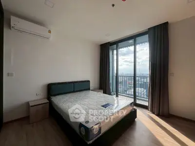 Spacious bedroom with large window and balcony offering stunning city views.