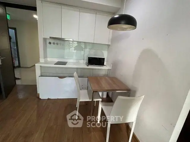 Modern kitchen with sleek white cabinets and cozy dining area in a stylish apartment.