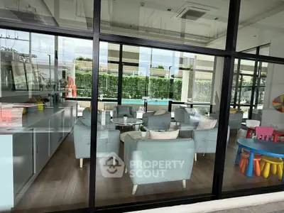 Modern communal lounge with pool view, featuring stylish seating and children's play area.