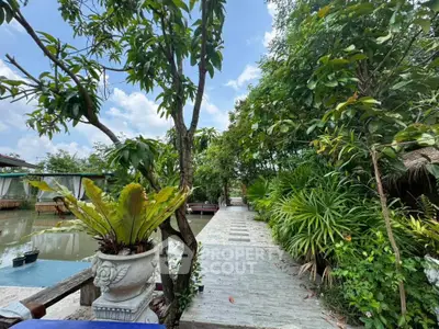Lush garden pathway with tropical plants and serene water view, perfect for tranquil living.