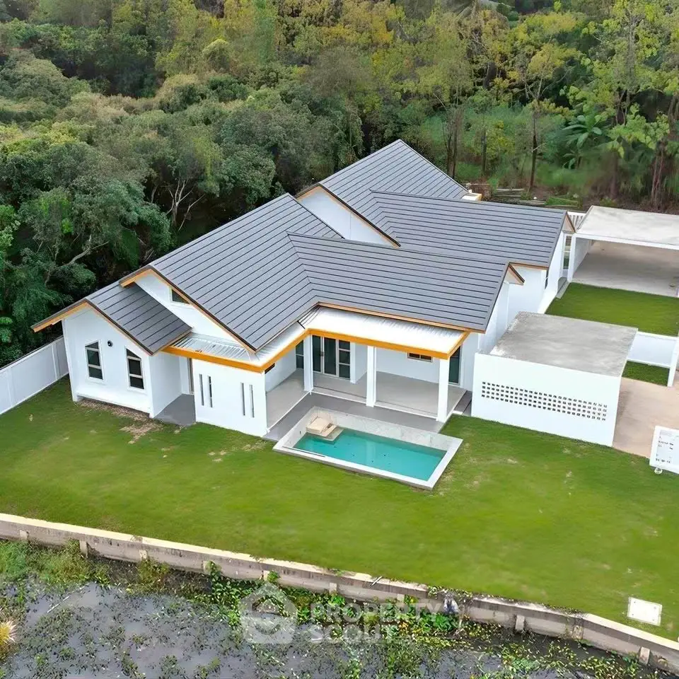 Stunning modern home with sleek roof design and private pool in lush green surroundings.