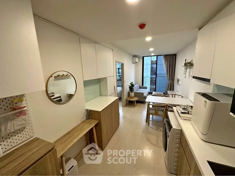 Modern apartment interior with open kitchen and cozy living area, featuring stylish decor and ample natural light.