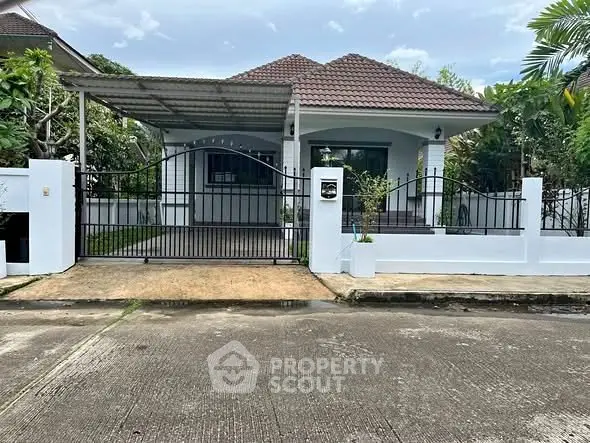 Charming single-story house with gated entrance and lush greenery, perfect for serene living.