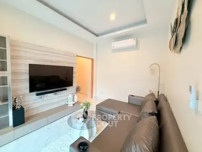 Modern living room with sleek furniture and wall-mounted TV, featuring elegant decor and ambient lighting.