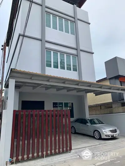 Modern three-story building with carport and sleek design in urban setting.