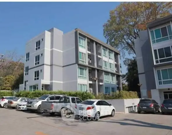 Modern apartment building with parking area and lush greenery
