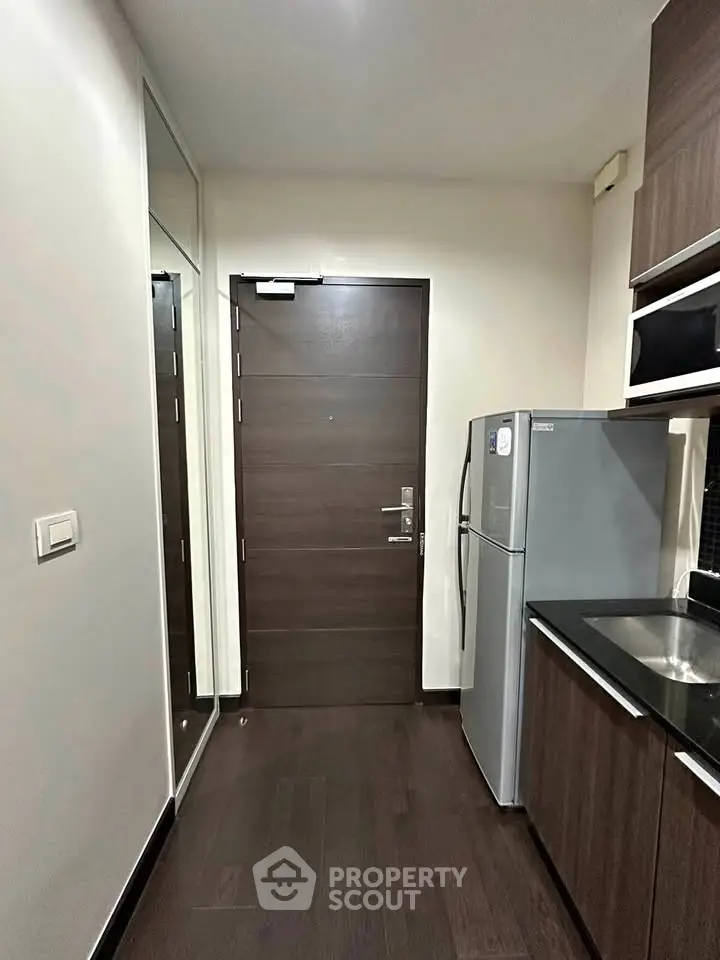 Modern kitchen with sleek cabinetry and stainless steel fridge in a compact layout.