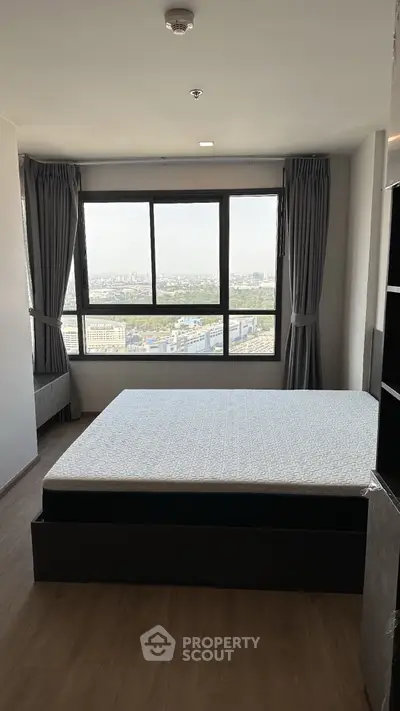 Spacious bedroom with large window offering stunning city views, modern design and ample natural light.