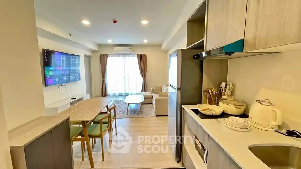 Modern open-plan living room and kitchen with stylish furniture and large TV