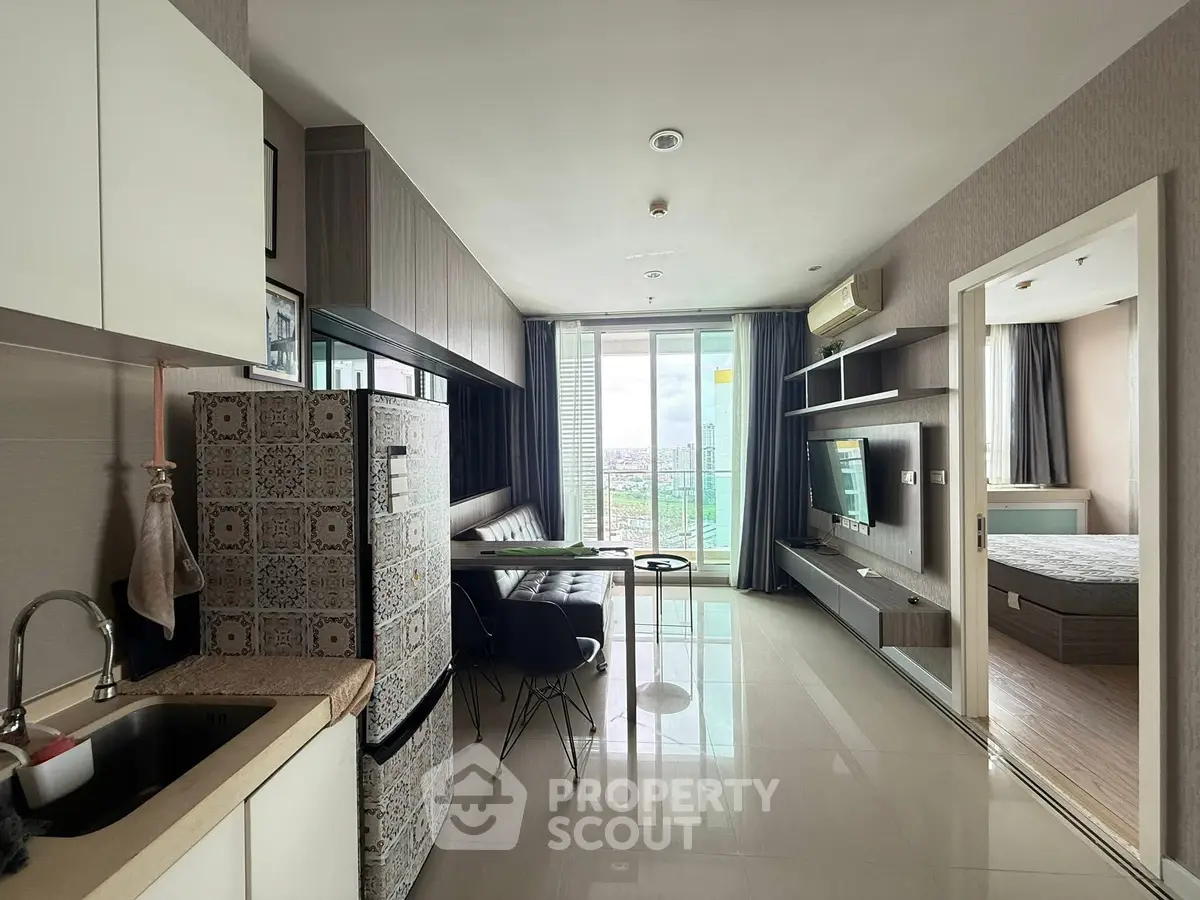 Modern open-plan living room with kitchen and balcony view in stylish apartment.