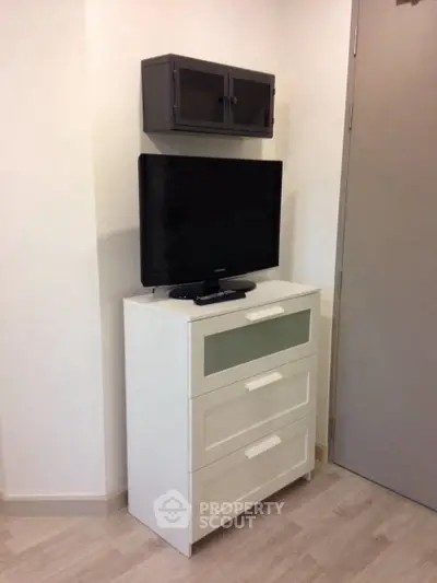 Modern living room corner with TV on white cabinet and wall-mounted storage.