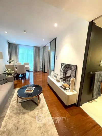 Modern living room with elegant decor and open layout, featuring hardwood floors and stylish furniture.