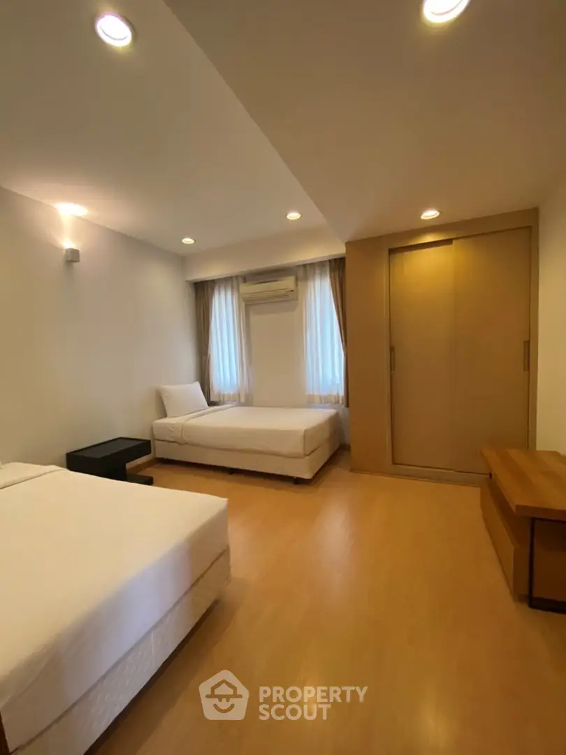 Spacious bedroom with twin beds and modern wooden flooring, perfect for comfortable living.